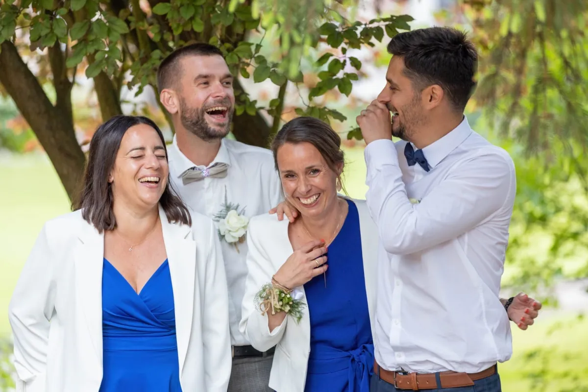 Mariés et invités éclatant de rire dans un jardin