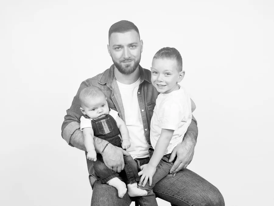 Papa et ses deux garçons sur fond uni, en noir et blanc
