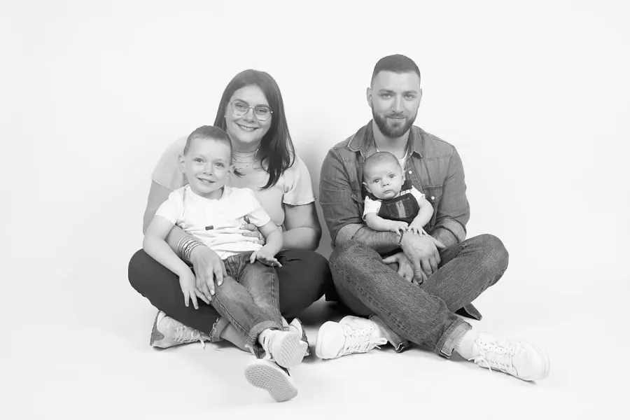 Parents et leurs deux enfants assis sur fond uni, en noir et blanc