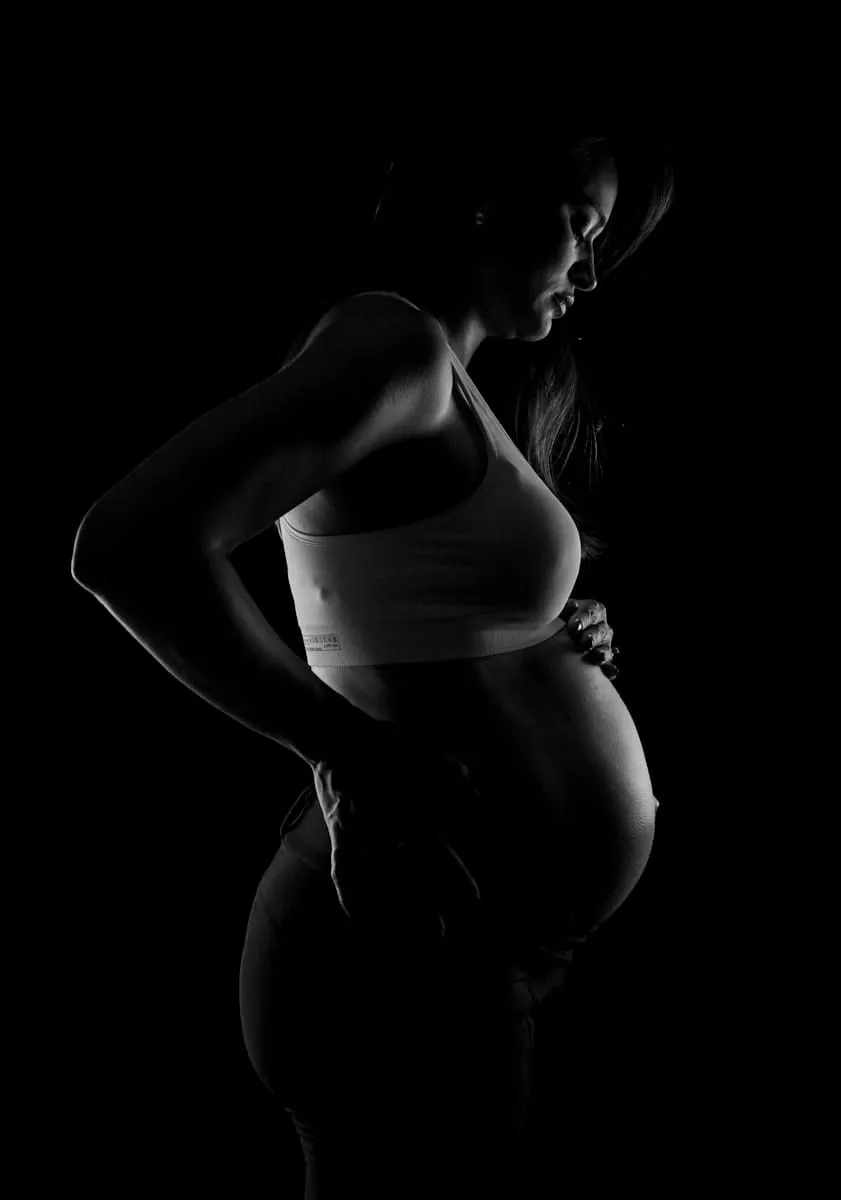 Silhouette d'une femme enceinte en clair-obscur, sur fond noir