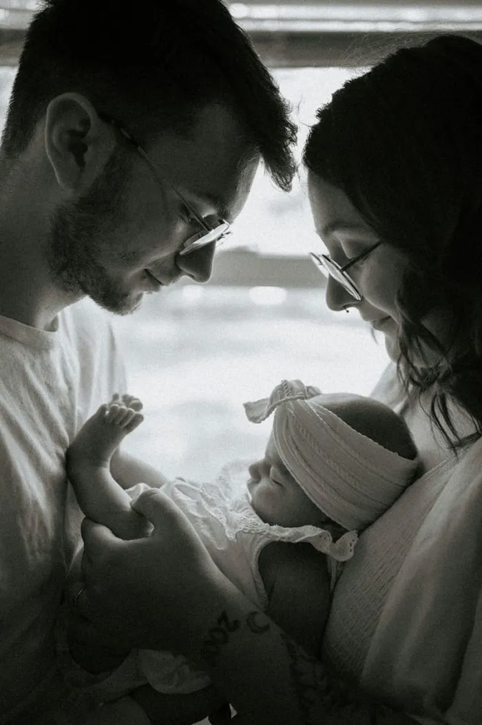 Parents penchés sur leur nouveau-né, en noir et blanc