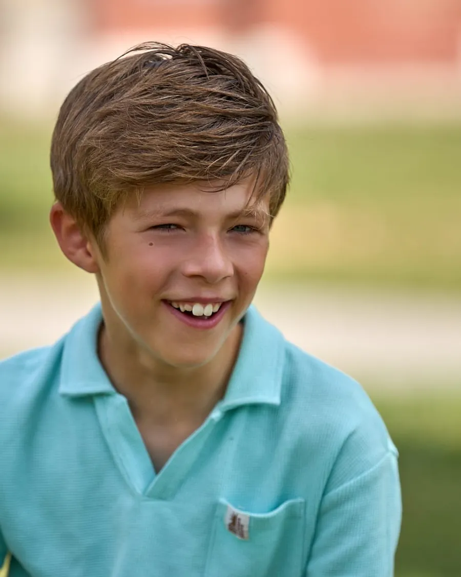 Portrait d'un garçon souriant en polo turquoise, en extérieur