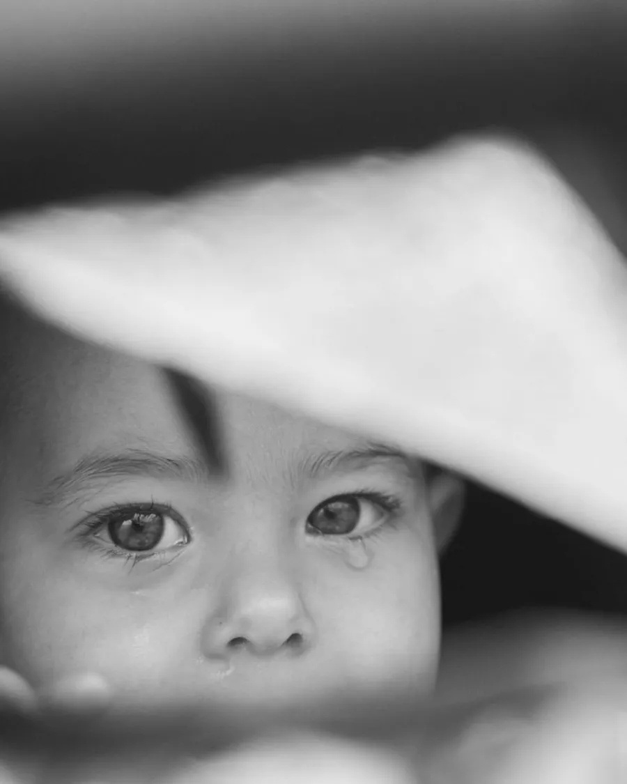 Regard d'enfant sous le bord d'un chapeau, en noir et blanc