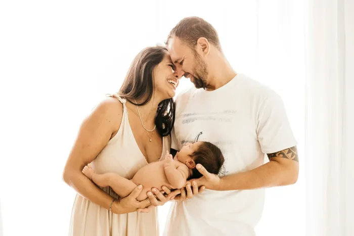 Couple souriant se regardant, leur bébé endormi dans les bras